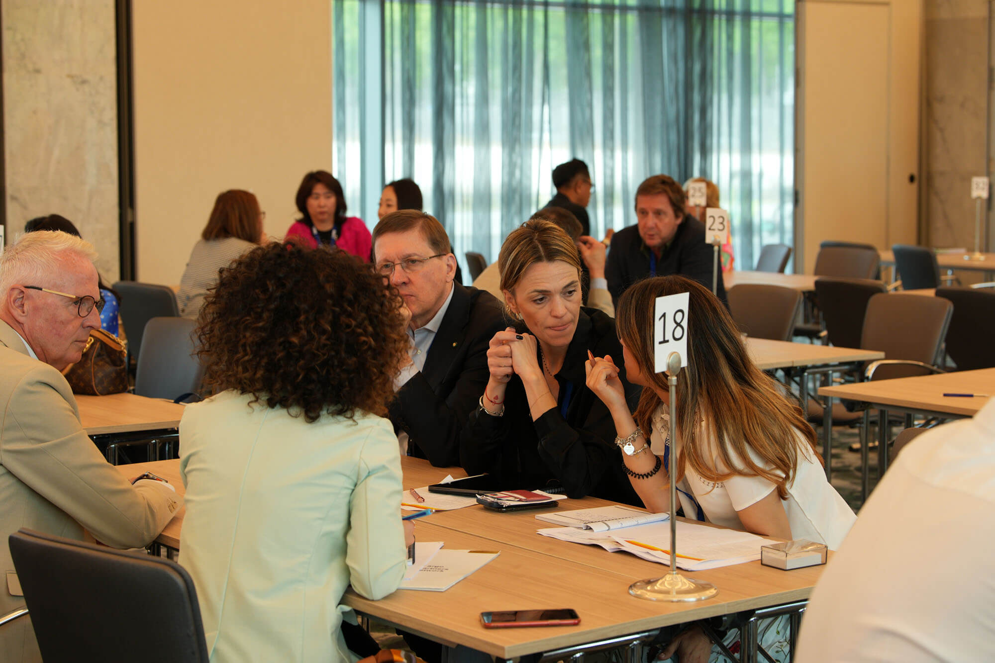 Delegates in conversation at numbered tables during one-to-one meetings